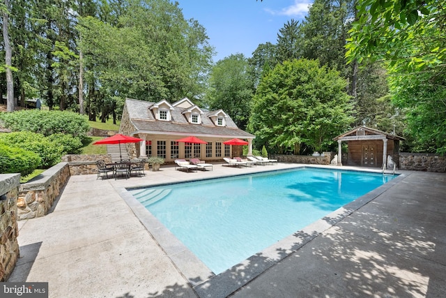 view of pool with a patio area and an outbuilding