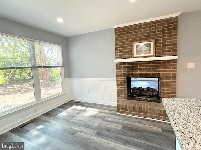 unfurnished living room with wood-type flooring and a brick fireplace