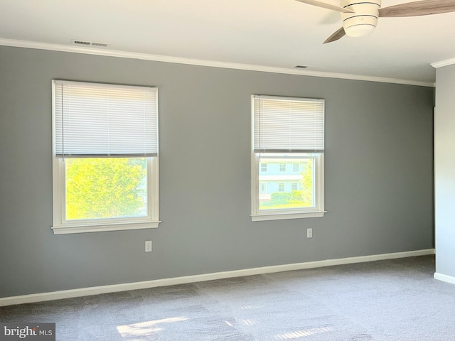 carpeted spare room with ceiling fan, a healthy amount of sunlight, and crown molding