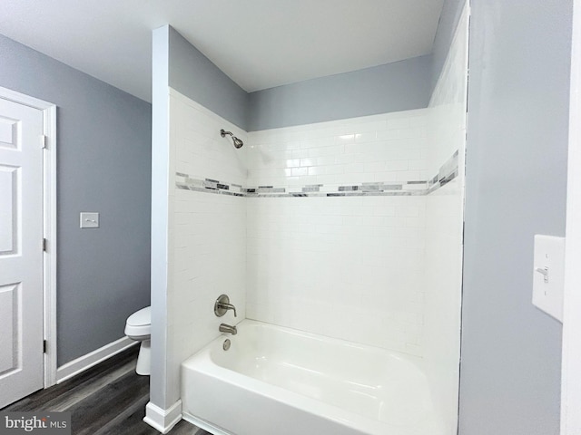 bathroom with hardwood / wood-style floors, tiled shower / bath, and toilet