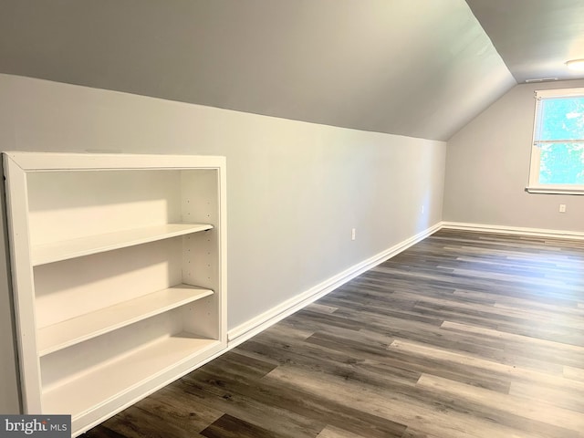 bonus room with vaulted ceiling and dark wood-type flooring