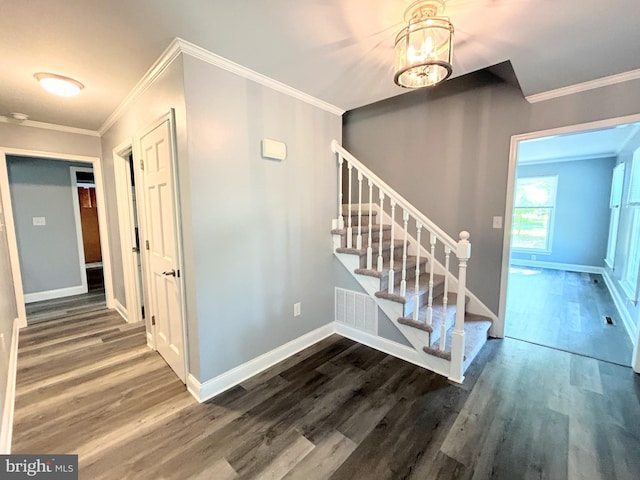 staircase featuring ornamental molding, a notable chandelier, and hardwood / wood-style flooring