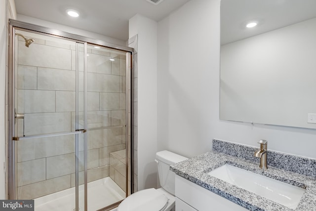 bathroom featuring vanity, toilet, and a shower with door