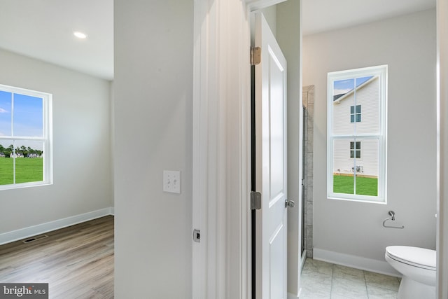 bathroom featuring hardwood / wood-style floors, toilet, and a healthy amount of sunlight