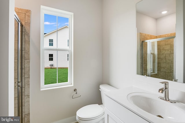 bathroom with an enclosed shower, vanity, a wealth of natural light, and toilet