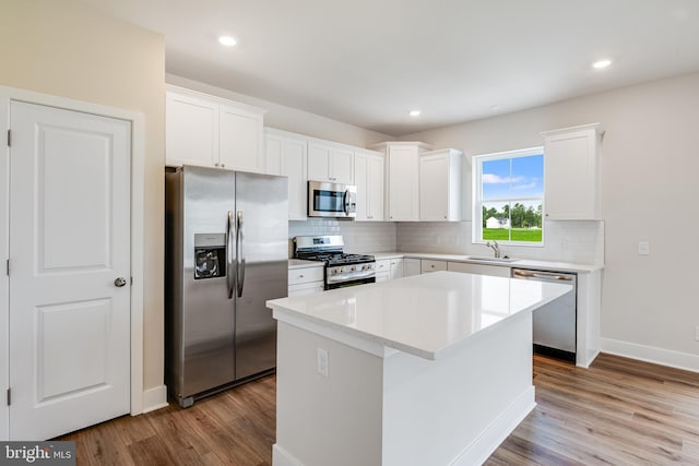 kitchen featuring sink, appliances with stainless steel finishes, white cabinetry, backsplash, and a kitchen island