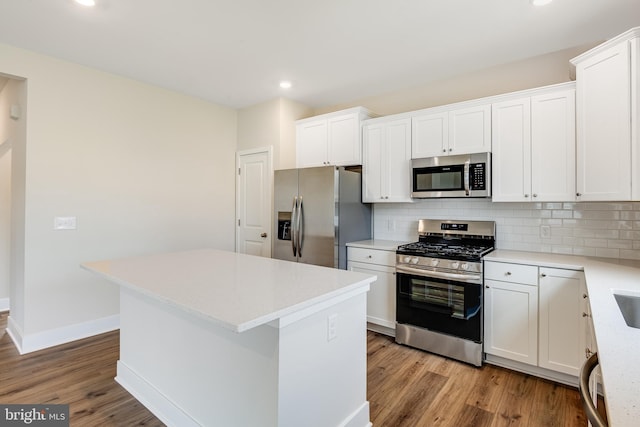 kitchen featuring backsplash, stainless steel appliances, a kitchen island, and white cabinets