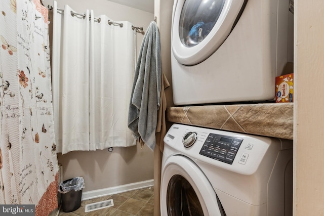 laundry room with tile patterned floors and stacked washer / dryer