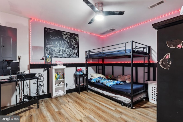 bedroom with electric panel, ceiling fan, and hardwood / wood-style floors