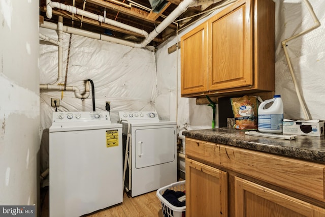 laundry area with cabinets, washer and clothes dryer, and light hardwood / wood-style floors