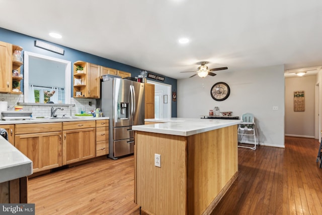 kitchen featuring ceiling fan, a center island, stainless steel fridge with ice dispenser, light hardwood / wood-style floors, and decorative backsplash