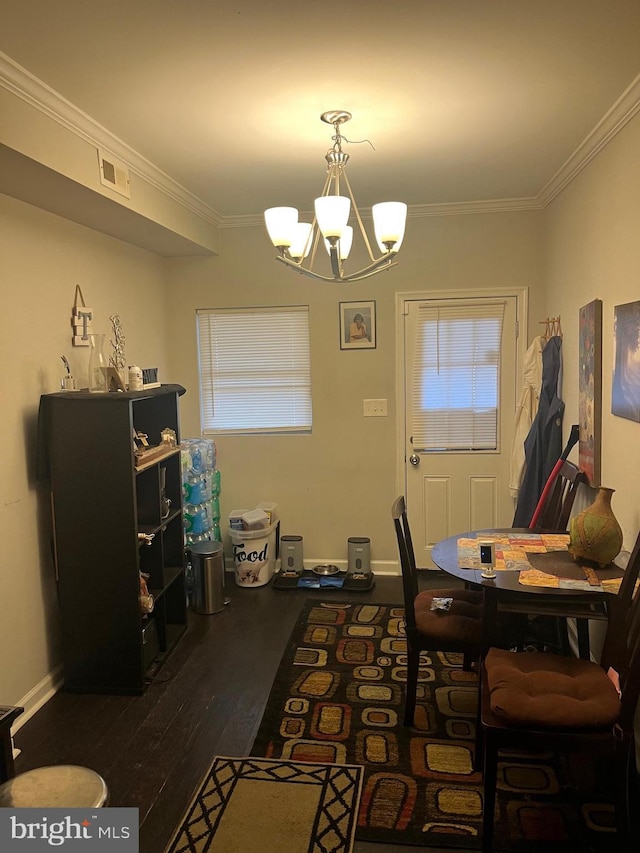 dining area featuring ornamental molding, dark wood-type flooring, and an inviting chandelier