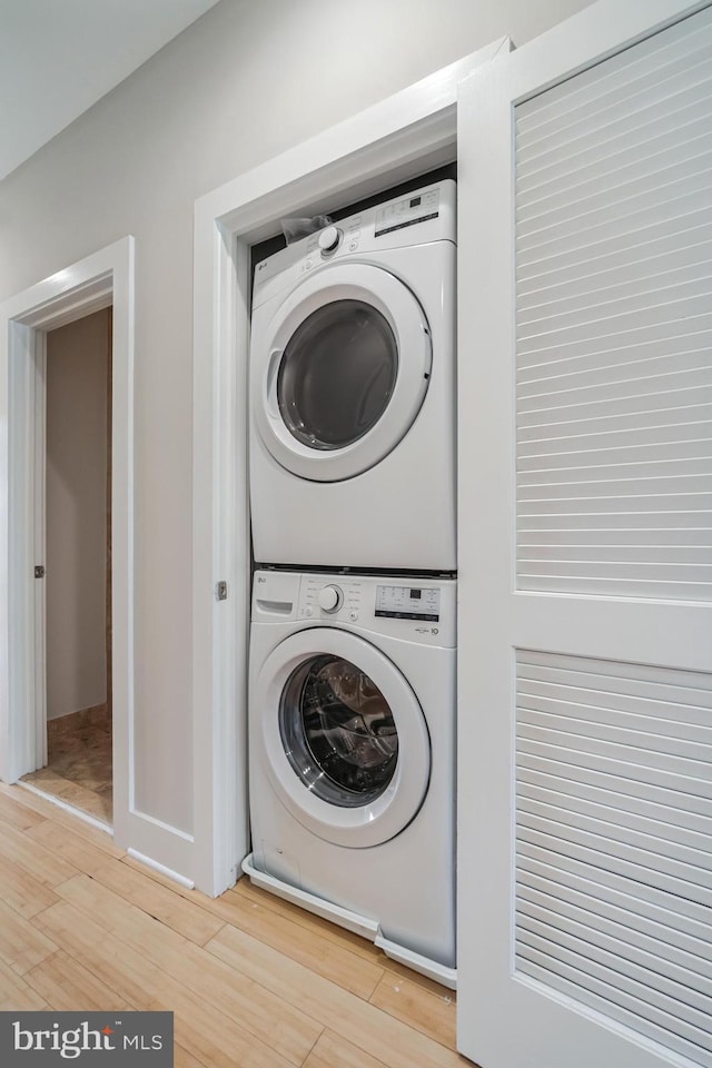 laundry room featuring hardwood / wood-style flooring and stacked washer and clothes dryer