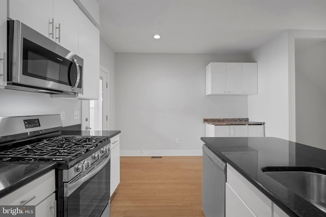 kitchen with white cabinets, stainless steel appliances, and light hardwood / wood-style flooring