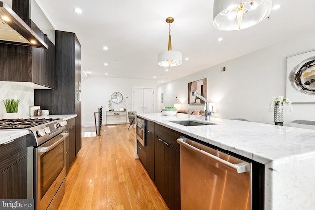 kitchen featuring light stone counters, backsplash, stainless steel stove, exhaust hood, and light wood-type flooring