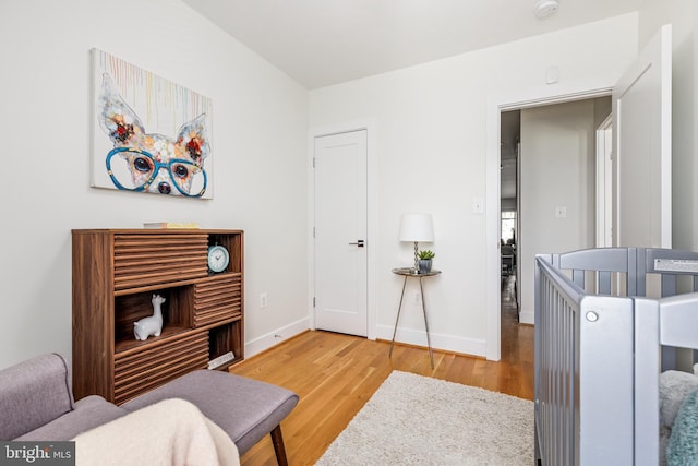 bedroom with a crib and wood-type flooring