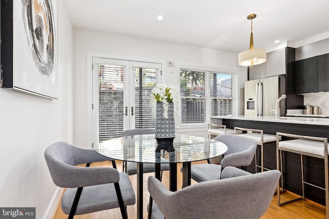 kitchen with decorative light fixtures, stainless steel refrigerator, wall chimney exhaust hood, and light hardwood / wood-style floors