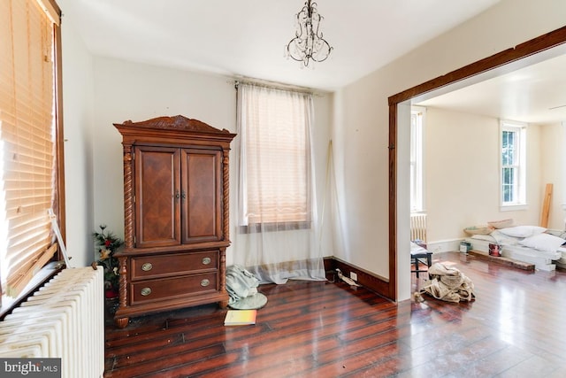 bedroom featuring radiator heating unit, dark wood-type flooring, and a notable chandelier