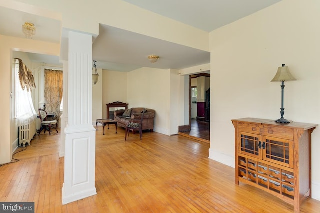 interior space featuring ornate columns, hardwood / wood-style floors, and radiator heating unit