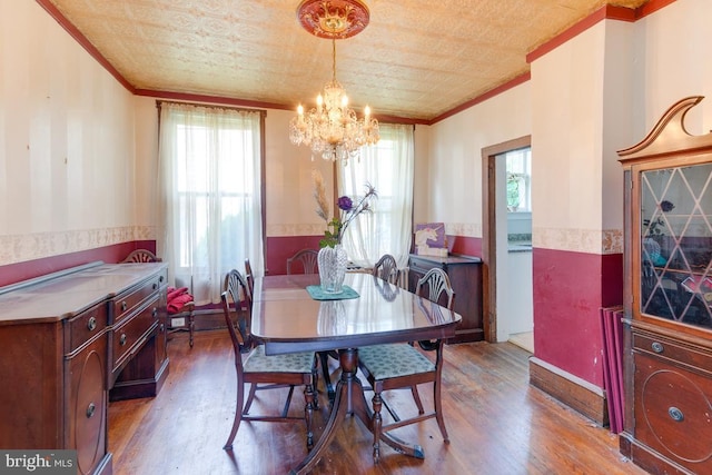 dining room with a chandelier, ornamental molding, and hardwood / wood-style flooring