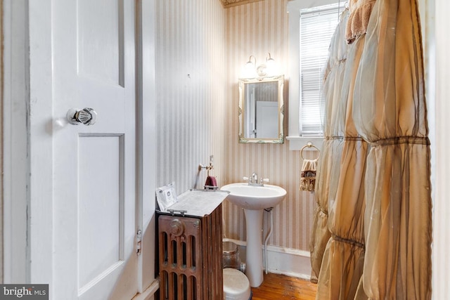 bathroom with hardwood / wood-style floors, radiator, and sink