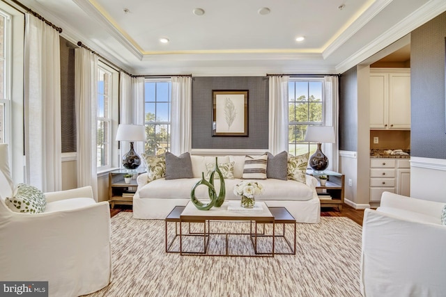 living area with light wood-type flooring, ornamental molding, and a tray ceiling