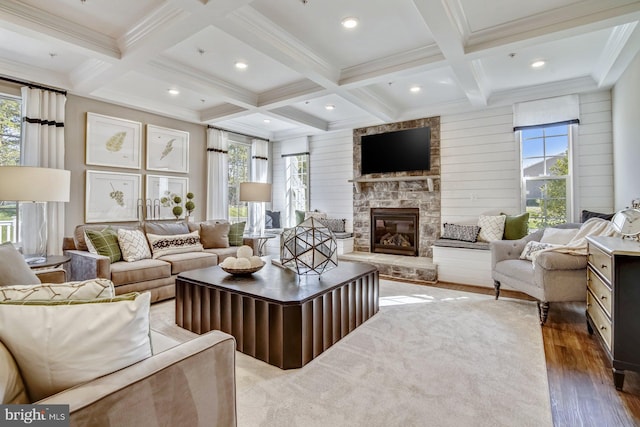 living room with coffered ceiling, beam ceiling, dark hardwood / wood-style floors, a stone fireplace, and wood walls