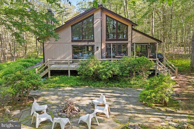 rear view of house featuring an outdoor fire pit and a wooden deck