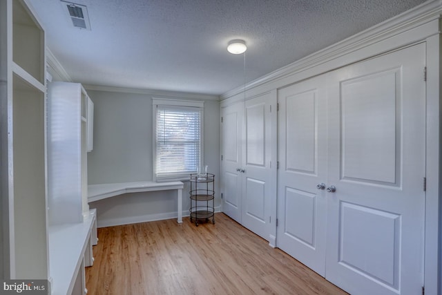 interior space with crown molding, a closet, a textured ceiling, and light wood-type flooring