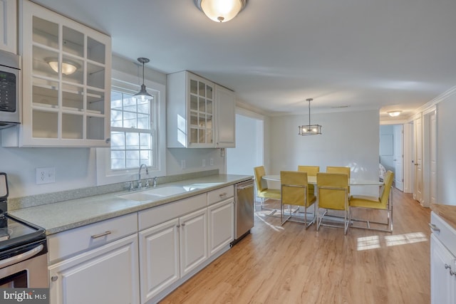 kitchen with pendant lighting, sink, white cabinets, and stainless steel appliances