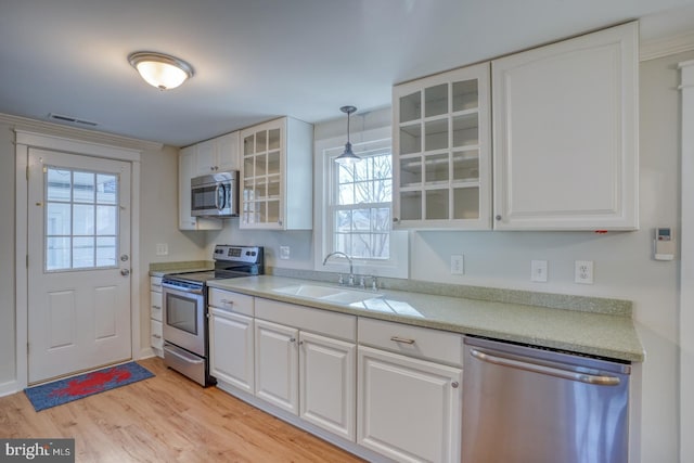 kitchen with pendant lighting, stainless steel appliances, white cabinetry, and sink