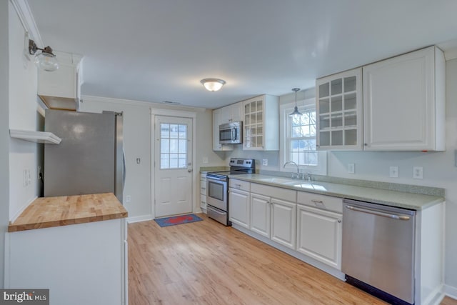 kitchen featuring pendant lighting, wooden counters, white cabinets, sink, and stainless steel appliances