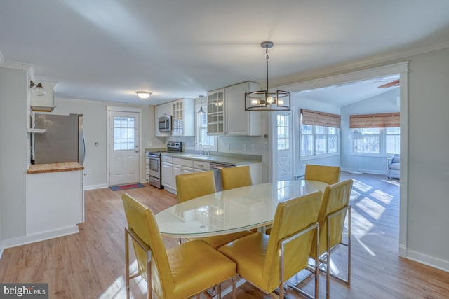 dining room featuring ornamental molding, sink, light hardwood / wood-style flooring, a chandelier, and lofted ceiling