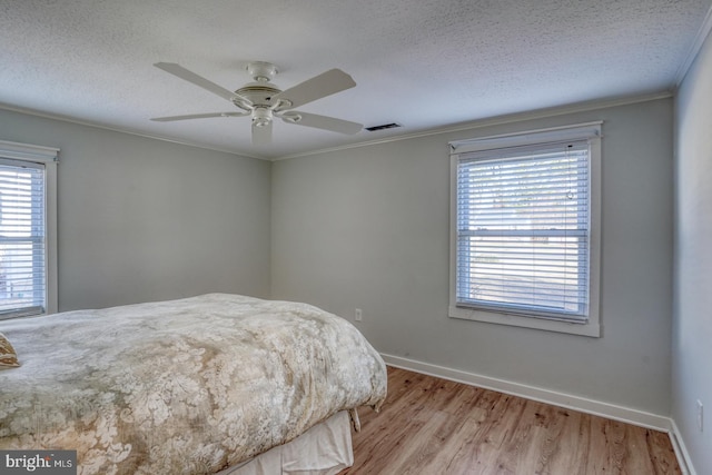 bedroom featuring multiple windows, ceiling fan, crown molding, and light hardwood / wood-style flooring