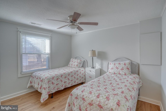 bedroom featuring ceiling fan, ornamental molding, a textured ceiling, and hardwood / wood-style flooring