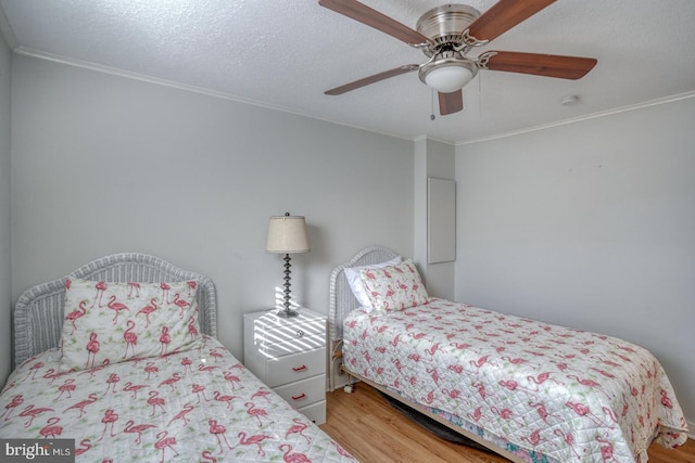 bedroom with hardwood / wood-style floors, a textured ceiling, ceiling fan, and ornamental molding