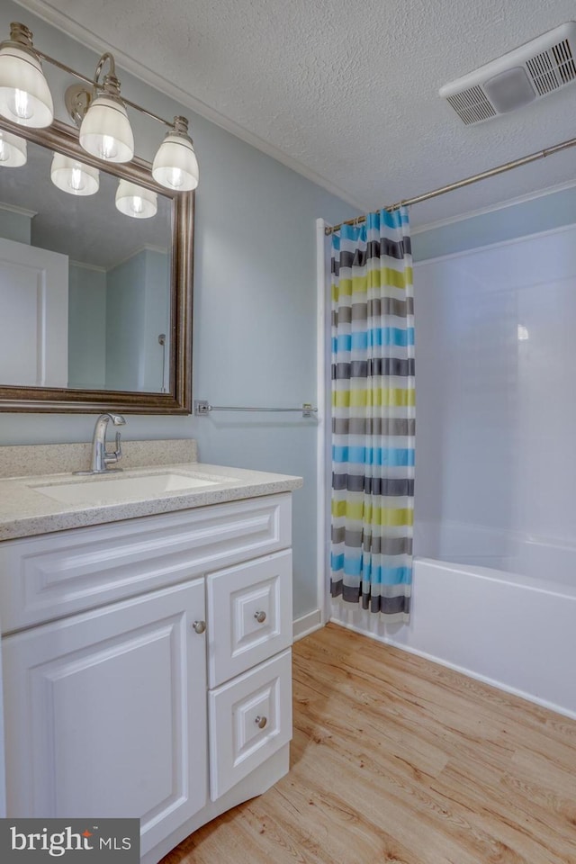 bathroom with vanity, a textured ceiling, hardwood / wood-style flooring, and shower / bathtub combination with curtain