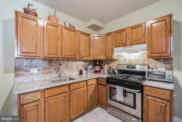 kitchen featuring backsplash, gas range, sink, and light tile patterned floors