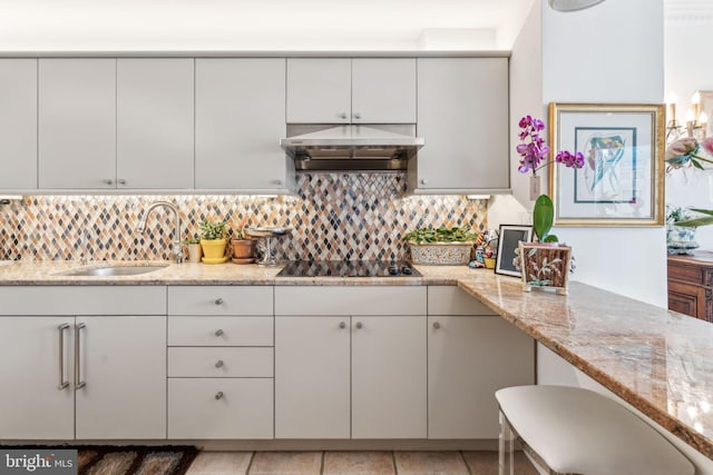 kitchen with light stone countertops, sink, backsplash, black electric cooktop, and white cabinets