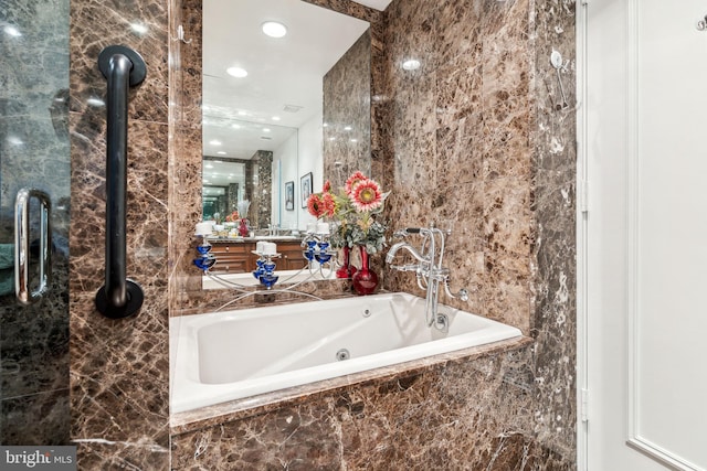 bathroom featuring vanity, tile walls, and tiled tub