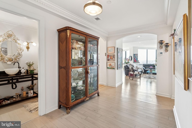 hallway with light hardwood / wood-style floors, crown molding, and sink