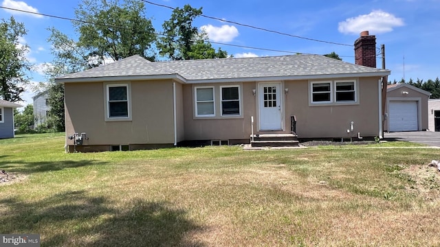 view of front of house featuring a garage, an outbuilding, and a front lawn