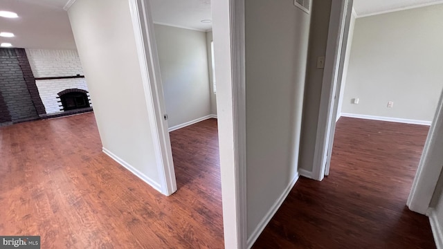 hall featuring ornamental molding, dark wood-type flooring, and brick wall