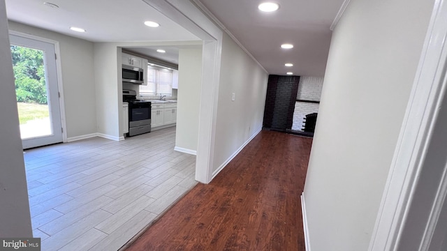 hallway with sink, ornamental molding, and hardwood / wood-style flooring