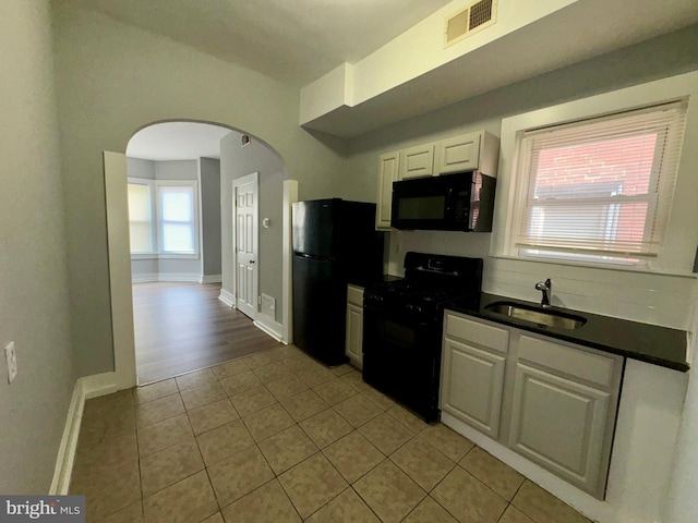 kitchen with light tile patterned floors, sink, white cabinetry, and black appliances