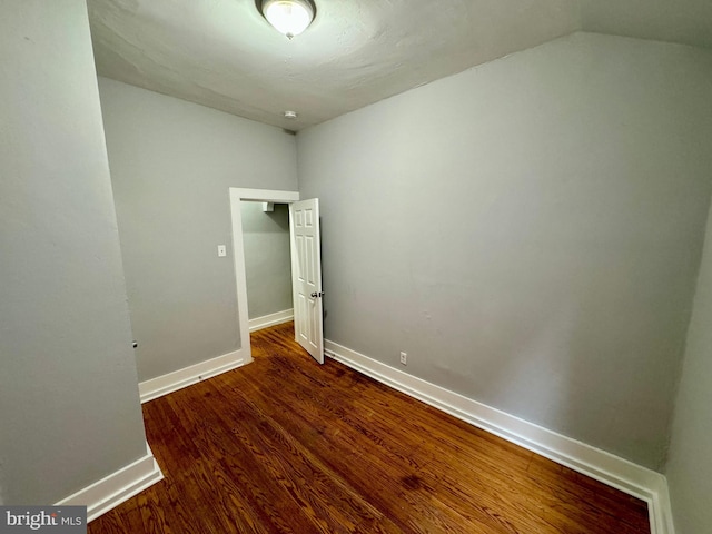 spare room featuring lofted ceiling and dark wood-type flooring