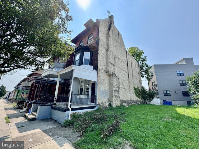 view of home's exterior featuring a porch and a lawn