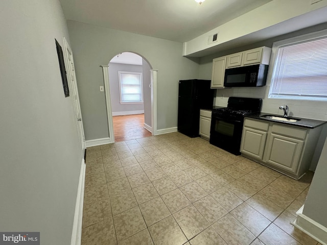 kitchen featuring decorative backsplash, sink, light tile patterned flooring, and black appliances