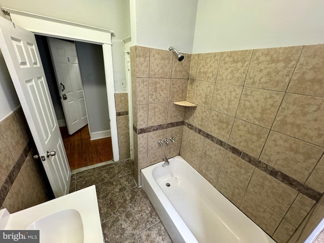 bathroom with tile walls and tiled shower / bath combo