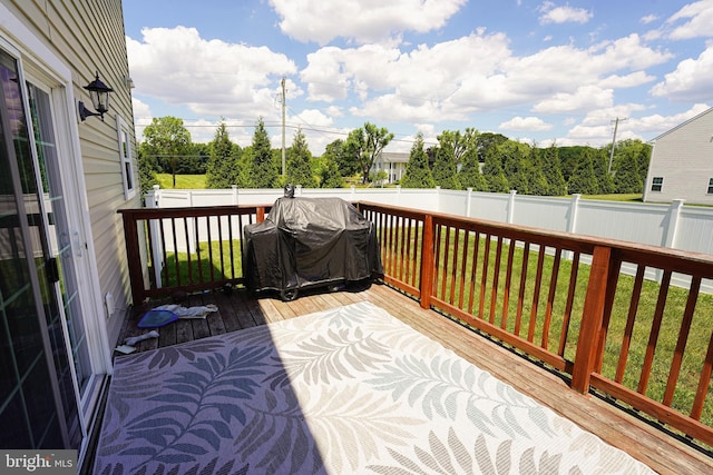 wooden terrace featuring area for grilling and a lawn